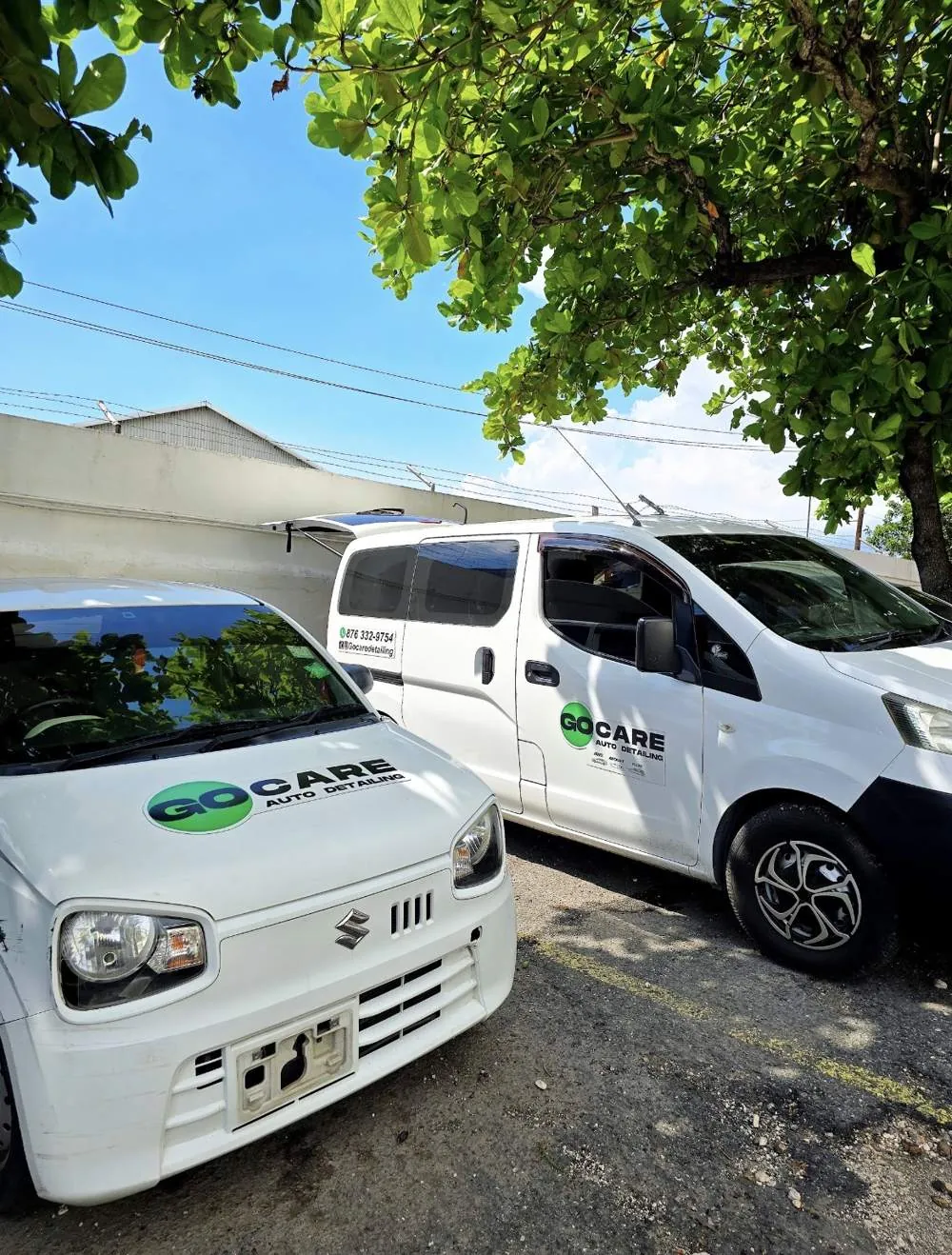 Two Go Care vehicles parked under a tree
