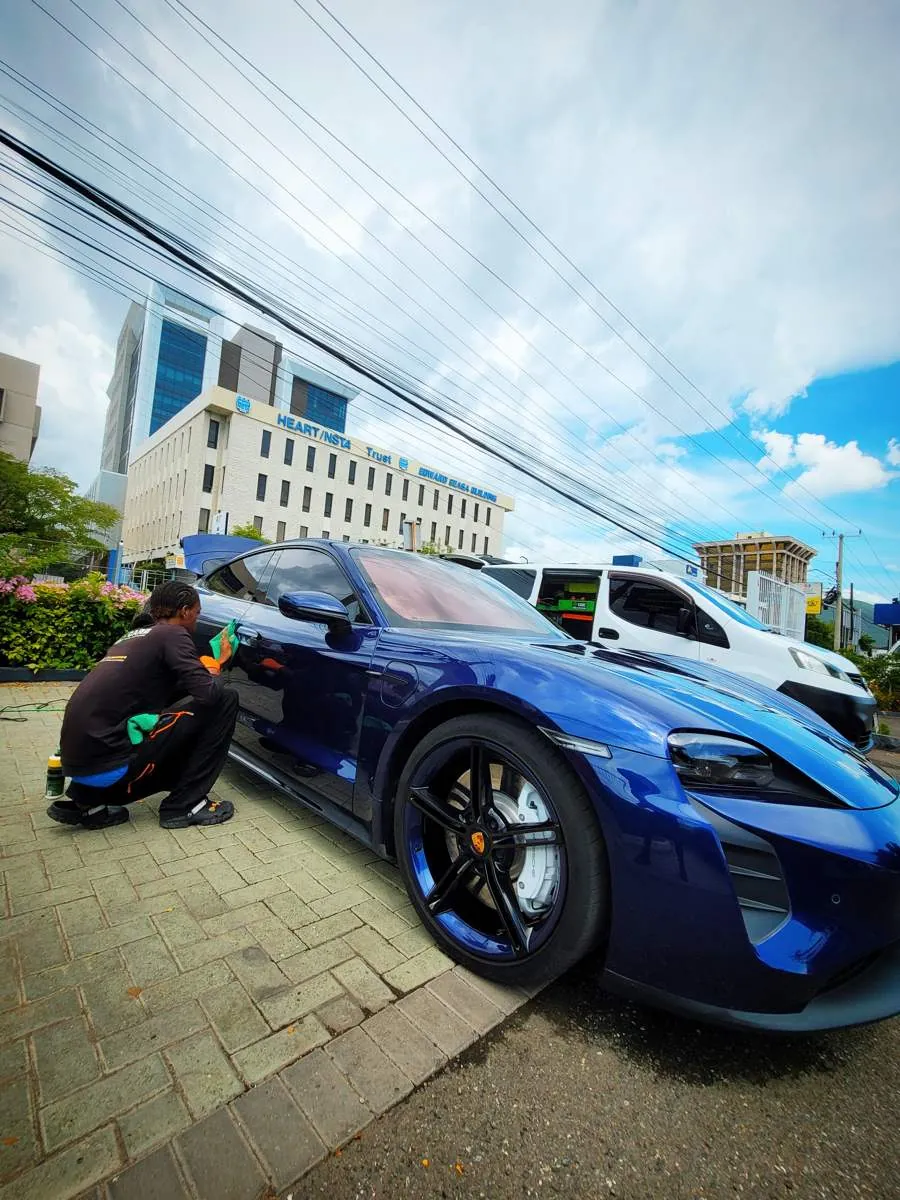 Technician detailing a blue Porsche Taycan