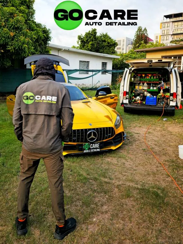 Go Care technician looking over a gold Mercedes-AMG next to the mobile detailing van